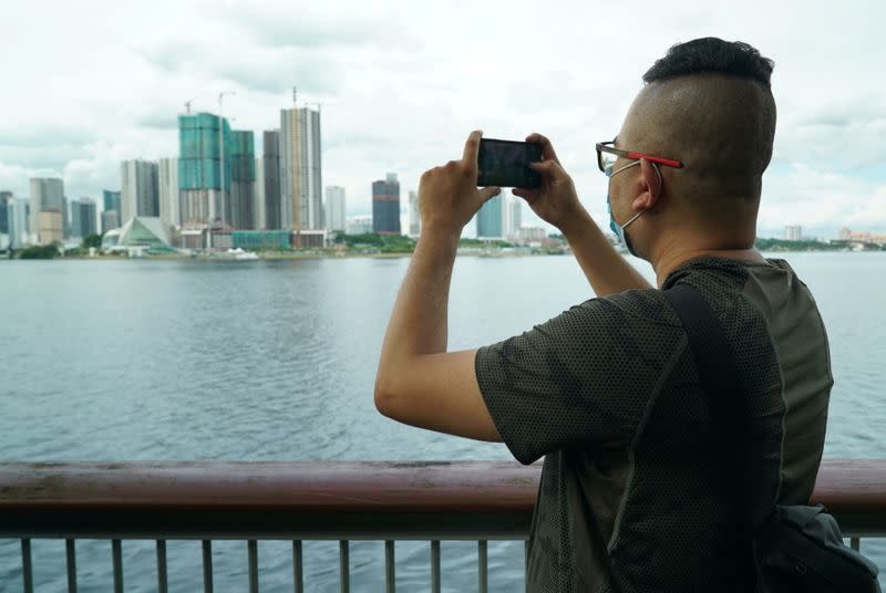 Singaporean Mohammad Faris Abdullah, 37, uses his phone for taking pictures of Johor Bahru ahead of his trip back to Malaysia after being separated from his family for two years amid the COVID-19 pandemic, at a walkway near the causeway in Singapore