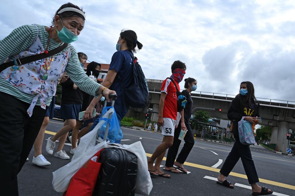 People cross a street in Singapore on June 23, 2020. - Singapore's Prime Minister Lee Hsien Loong called a general election "like no other" on June 23 as the city-state struggles to recover from a major coronavirus outbreak that has swept through crowded migrant worker dormitories. (Photo by Roslan RAHMAN / AFP) (Photo by ROSLAN RAHMAN/AFP via Getty Images)