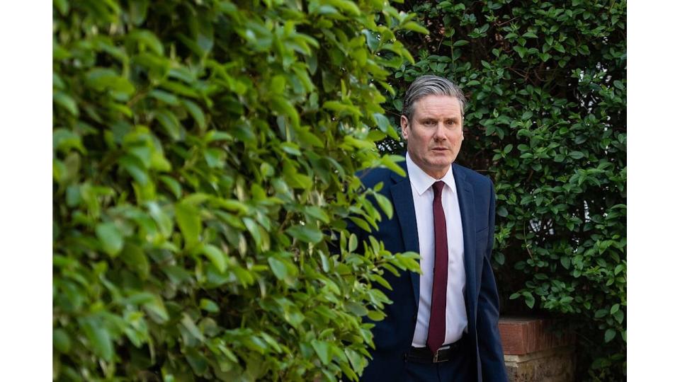 Keir Starmer in a suit next to a hedge