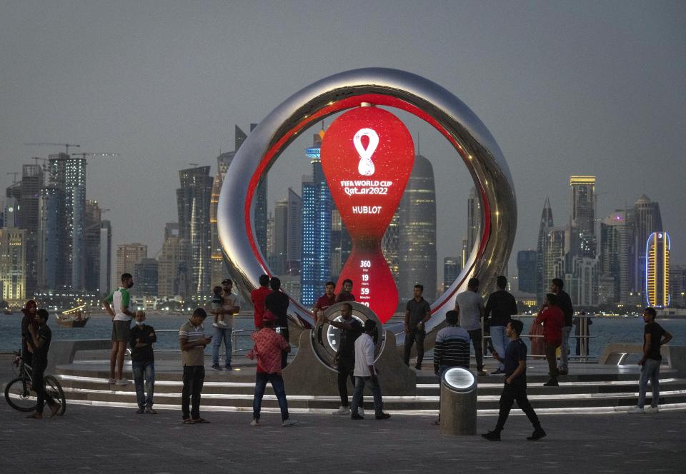 FILE - People gather around the official countdown clock showing remaining time until the kick-off of the World Cup 2022, in Doha, Qatar, Thursday, Nov. 25, 2021. Qatar is a devoutly apolitical place, with speech and assembly heavily restricted and a large population of foreign workers who could lose their livelihoods if they cause a stir. But that could change next month, when an estimated 1.2 million soccer fans descend on the tiny Gulf Arab nation for the World Cup. (AP Photo/Darko Bandic, File)