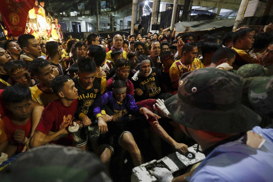 Filipino Roman Catholic devotees are pushed by police and military as they try to break the barriers to go near the carriage of the Black Nazarene during a raucous procession to celebrate its feast day Thursday, Jan. 9, 2020, in Manila, Philippines. A mammoth crowd of mostly barefoot Filipino Catholics prayed for peace in the increasingly volatile Middle East at the start Thursday of an annual procession of a centuries-old black statue of Jesus Christ in one of Asia's biggest religious events. (AP Photo/Aaron Favila)