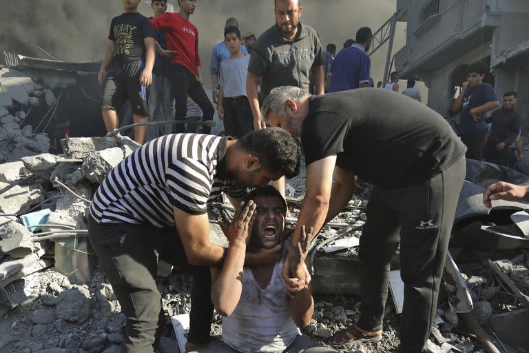 Dos palestinos consuelan a un hombre que llora tras perder familiares bajo los escombros, de una casa destruida tras un ataque aéreo israelí en Ciudad de Gaza, el sábado 4 de noviembre de 2023. (AP Foto/Abed Khaled)