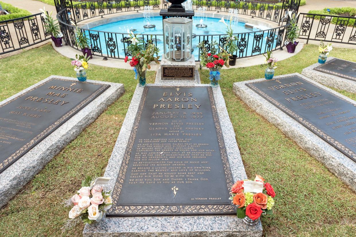 Elvis Presley's grave at Graceland, Memphis, Tennessee with three other graves with a round pool and an elaborate black fence