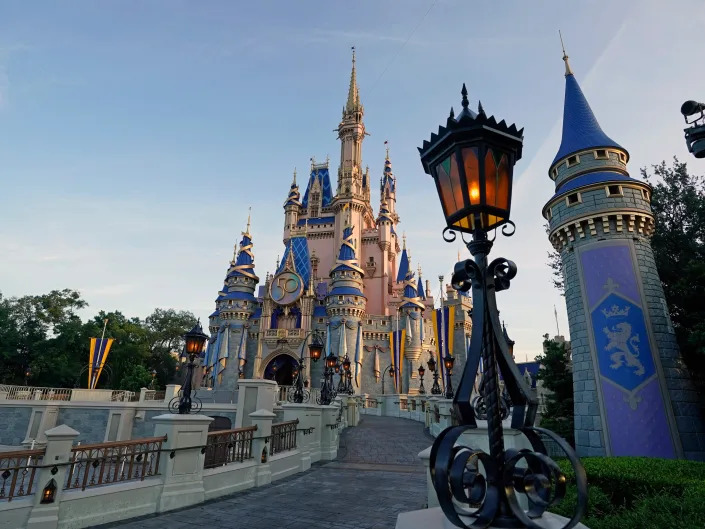 Photo from low street view of a tall Cinderella's castle and lamp post.