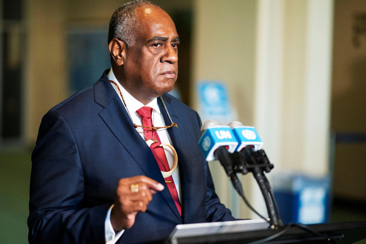 Alatoi Ishmael Kalsakau stands at a podium with two microphones, one bearing a sign that reads: UN