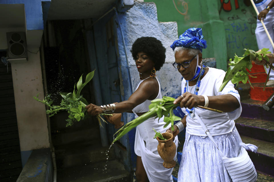 Members of the Mocidade Unida do Santa Marta samba school perform a washing ritual for good luck called "Lavagem" as they attend a ceremony marking Black Consciousness Day in the Santa Marta favela of Rio de Janeiro, Brazil, Friday, Nov. 20, 2020. Brazilians celebrate the holiday with Afro-Brazilian dance, music and religious ceremonies, reflecting the deep cultural and social ties of the Black community to the country’s history and honor legendary anti-slave leader Zumbi dos Palmares on the day of his death. (AP Photo/Bruna Prado)