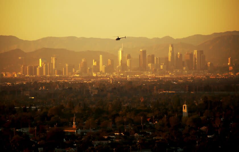 LONG BEACH, CALIF. - AUG. 16, 2022. A helicopter flies across the hazy atmosphere of the Los Angeles Basin as seen from Signal Hill. (Luis Sinco / Los Angeles Times)