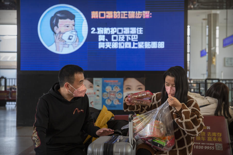 Travelers wear face masks as a screen shows a video about the proper way to wear a mask at the Beijing Railway Station in Beijing, Friday, Jan. 31, 2020. The U.S. advised against all travel to China on Friday after the World Health Organization declared the outbreak of a new virus that has spread to more than a dozen countries a global emergency. (AP Photo/Mark Schiefelbein)