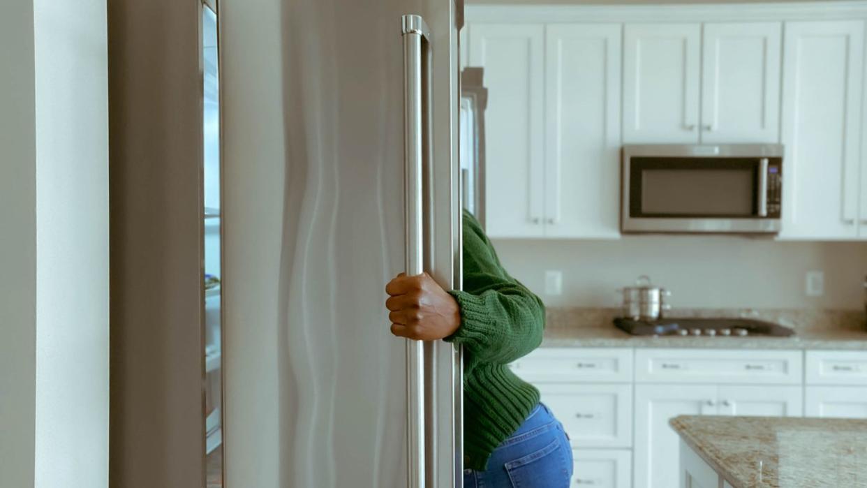 woman looks into refrigerator for healthy snack