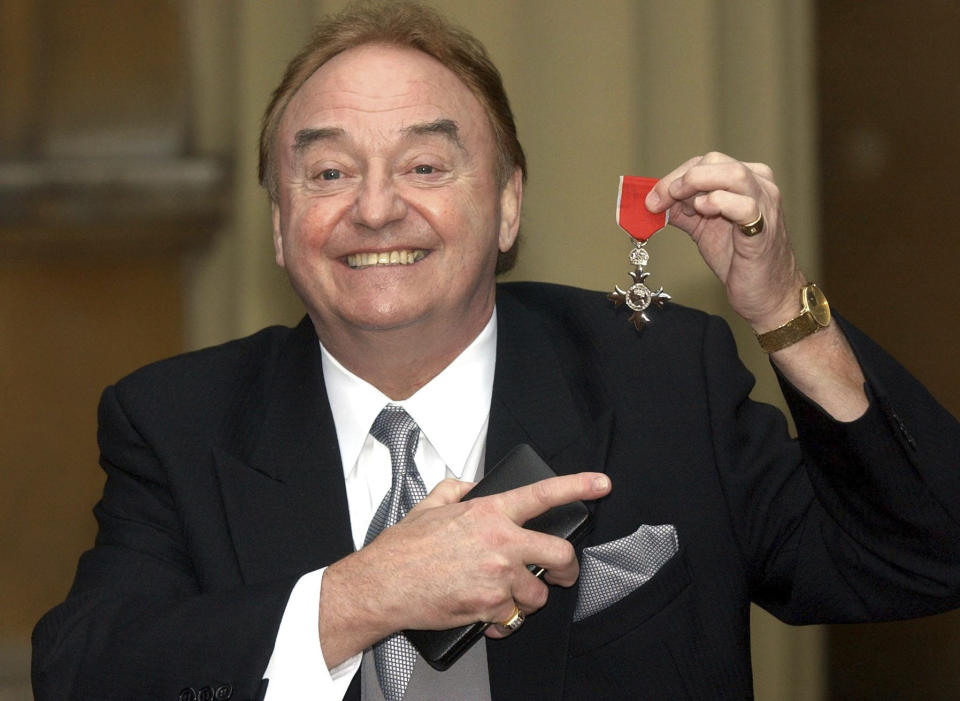 FILE - In this Dec. 12, 2003 file photo, Gerry Marsden holds his MBE. Gerry Marsden, the British singer and lead singer of Gerry and the Pacemakers, who was instrumental in turning a song from the Rodgers and Hammerstein musical “Carousel” into one of the great anthems in the world of football, has died. He was 78. (Matthew Fearn/PA via AP, File)