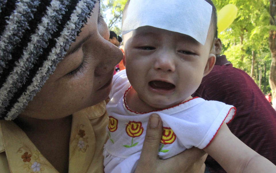 A Cambodian villager from countryside holds her baby as she waits for a medical check up for children outside a children hospital of Kuntha Bopha, in Phnom Penh, Cambodia, Monday, July 9, 2012. A deadly form of a common childhood illness has been linked to many of the mysterious child deaths in Cambodia that caused alarm after a cause could not immediately be determined, health officials said Monday. (AP Photo/Heng Sinith)