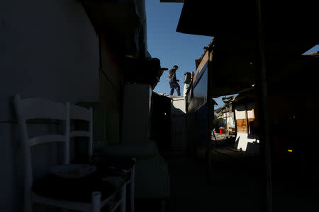 A scrap collector walks on roofs of empty huts after their inhabitants left the Roma shanty town of El Gallinero, on the outskirts of Madrid, Spain, September 25, 2018. REUTERS/Susana Vera