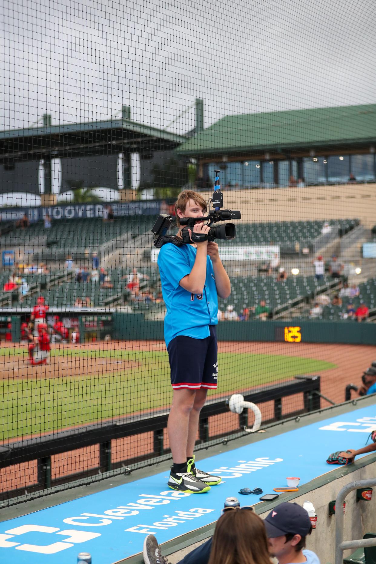 Zachary Hoffman spends time on top of the dugout at Roger Dean Chevrolet Stadium with a video camera, capturing theatrical moments in the stands that flash onto the scoreboard.