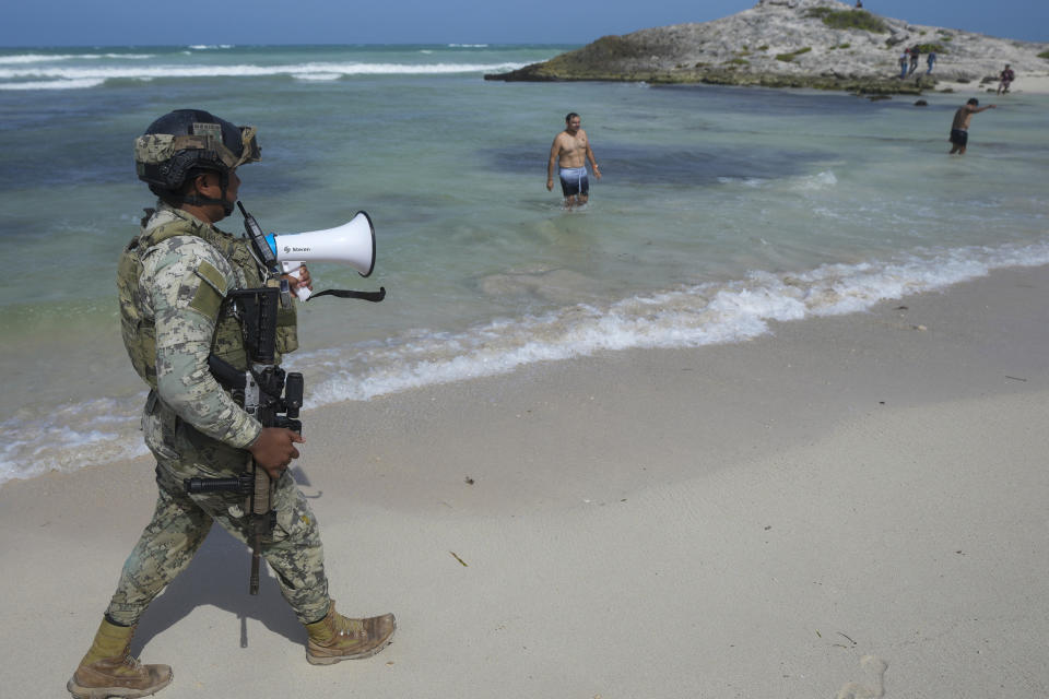 Un soldado les pide a turistas que evacúen la playa Mirador antes de la llegada del huracán Beryl, el jueves 4 de julio de 2024, en Tulum, México. (AP Foto/Fernando Llano)