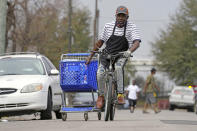 Mark Johnson pulls a shopping cart with cases of donated water back to his home, which was without running water after a recent winter storm, Friday, Feb. 26, 2021, in Houston. Local officials, including Houston Mayor Sylvester Turner, say they have focused their efforts during the different disasters on helping the underserved and under-resourced but that their work is far from complete. (AP Photo/David J. Phillip)