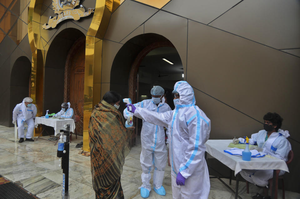 Baptist Church members wearing personal protective suits check the body temperature of devotees arriving to attend a Sunday service in Hyderabad, India, Sunday, Aug. 16, 2020. India is the third hardest-hit country by the pandemic in the world after the United States and Brazil. (AP Photo/Mahesh Kumar A.)