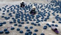 Women paint paper replicas of soldier's hats for the Vu Lan Festival at Dong Ho village, outside Hanoi August 7, 2014. Vietnam is celebrating the month-long festival of the hungry ghosts, also known as Vu Lan festival, where many Taoists and Buddhists believe that the living are supposed to please the ghosts by offering them food and burning paper effigies of homes, maids, and other daily items for spirits to use in the afterlife. REUTERS/Kham (VIETNAM - Tags: RELIGION SOCIETY TPX IMAGES OF THE DAY)