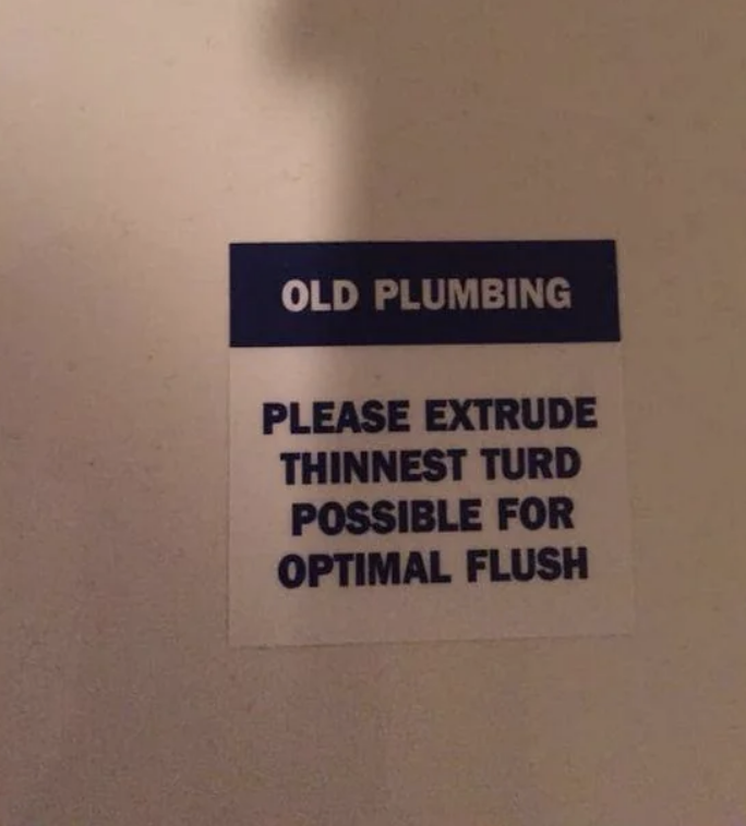 Sign reads "OLD PLUMBING PLEASE EXTRUDE THINNEST TURD POSSIBLE FOR OPTIMAL FLUSH" on a wall