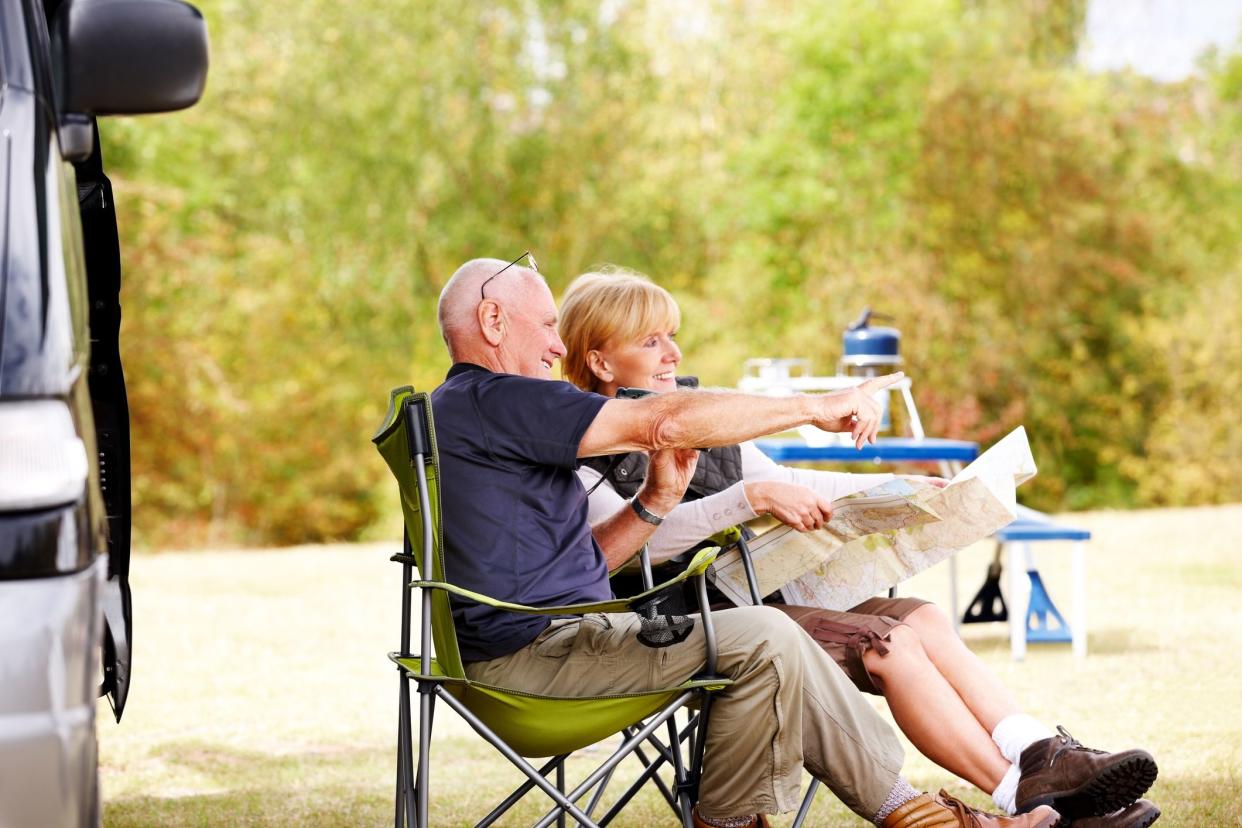 senior couple sitting outside camper van surverying landscape