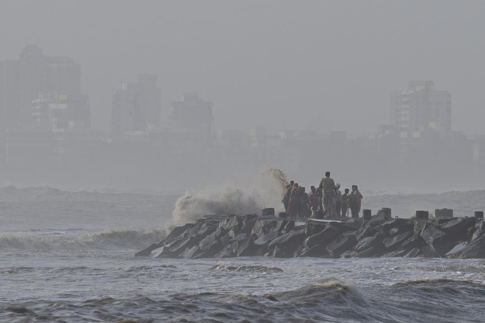 A police officer tries to move people away as high tide waves hit the Arabian Sea coast at Juhu Koliwada in Mumbai, India, Monday, June 12, 2023. Cyclone Biparjoy, the first severe cyclone in the Arabian Sea this year is set to hit the coastlines of India and Pakistan Thursday. (AP Photo/Rafiq Maqbool)