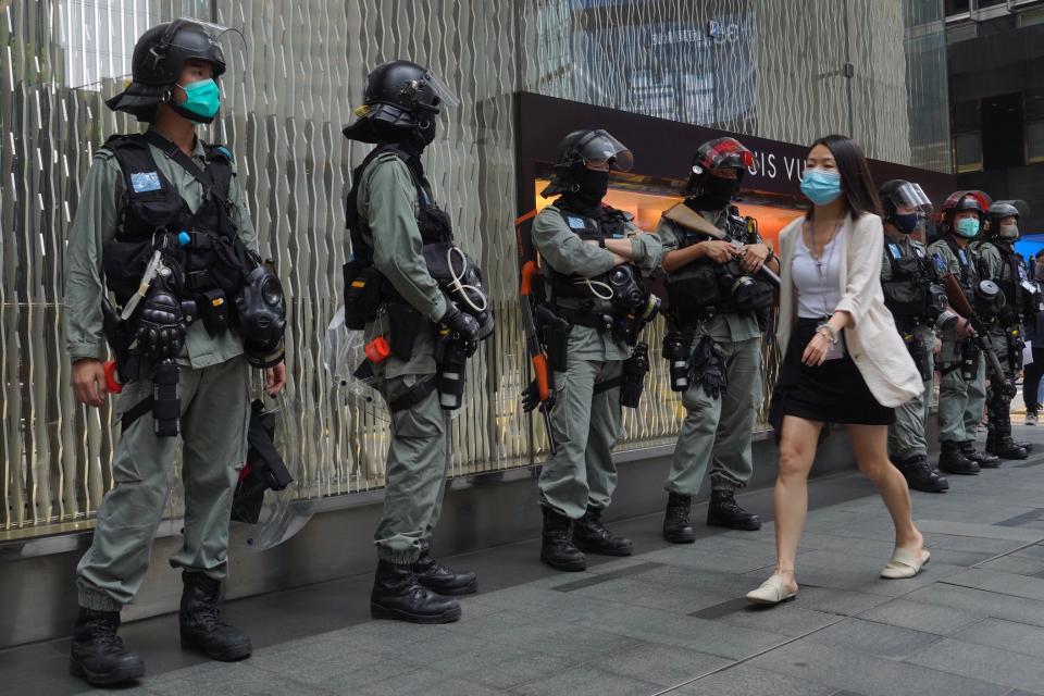 Image: A woman walks in front of riot police at Central during the second day of debate on a contentious bill that would criminalize insulting or abusing the Chinese national anthem, in Hong Kong (Vincent Yu / AP)