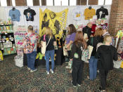 Fans of "The Golden Girls" TV show browse a merchandise booth in Chicago, Friday, April 22, 2022. Golden-Con, which lasts thru Sunday, is giving those who adored the NBC sitcom a chance to mingle, see panels and buy merchandise. The show, which ran from 1985-1992, starred Bea Arthur, Rue McClanahan, Estelle Getty and Betty White—who died at age 99 in December. (AP Photo/Terry Tang)
