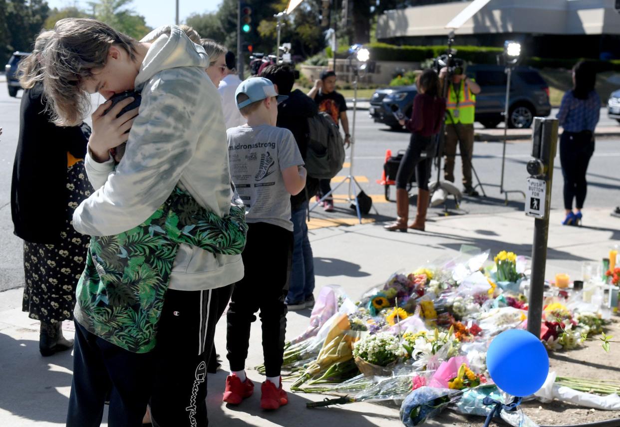 People hug at the Westlake High School memorial for Wesley Welling, 15, on Wednesday, the day after he was killed and three other students were injured by a driver who hit them near the campus. A community fundraiser Sunday night at The Canyon will benefit victims' families.