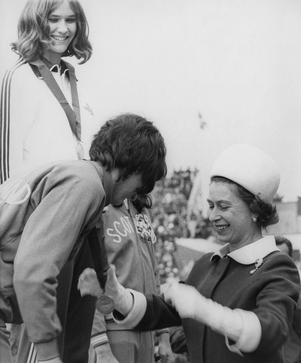 Queen Elizabeth II presents the silver medal for the High Jump to Ann Wilson of England, as gold medalist, Debbie Brill of Canada, looks on, at Meadowbank Stadium, during the British Commonwealth Games