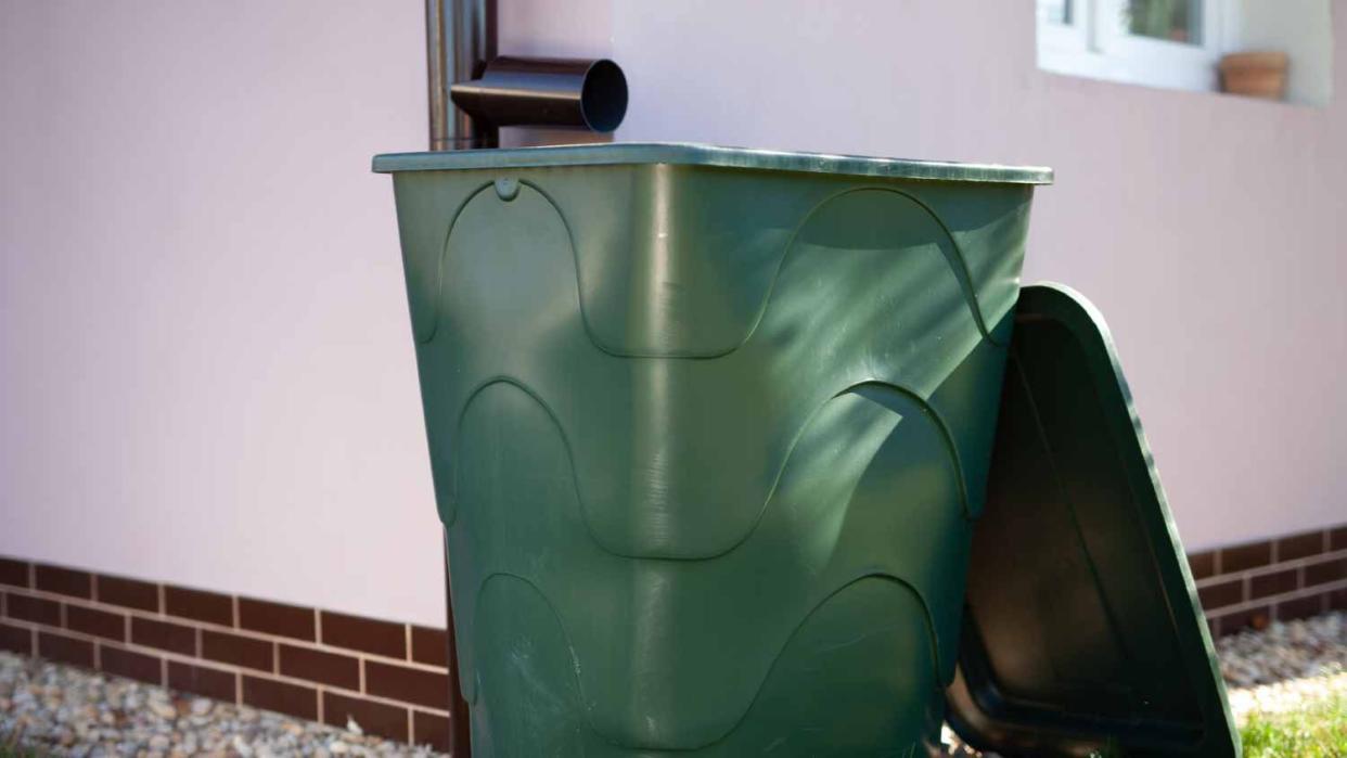 A plastic barrel outside in front of a house