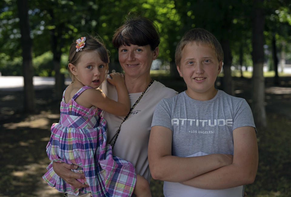 Kateryna Krupych sostiene en brazos a su hija Masha, de 4 años, mientras posa para una fotografía junto a su hijo Maksim, en Jersón, Ucrania, el 13 de junio de 2023. Krupych y sus hijos fueron rescatados luego de que tuviesen que abandonar su casa en la isla de Chaika, en la zona gris entre las líneas del frente. (AP Foto/Evgeniy Maloletka)