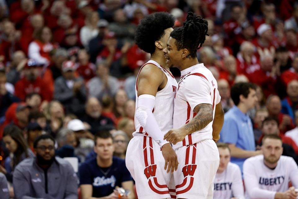 Kamari McGee, right, congratulates the Wisconsin Badgers' Chucky Hepburn after a goal in the first half of their game against the Liberty Flames in the second round of the NIT Men's Basketball Tournament.