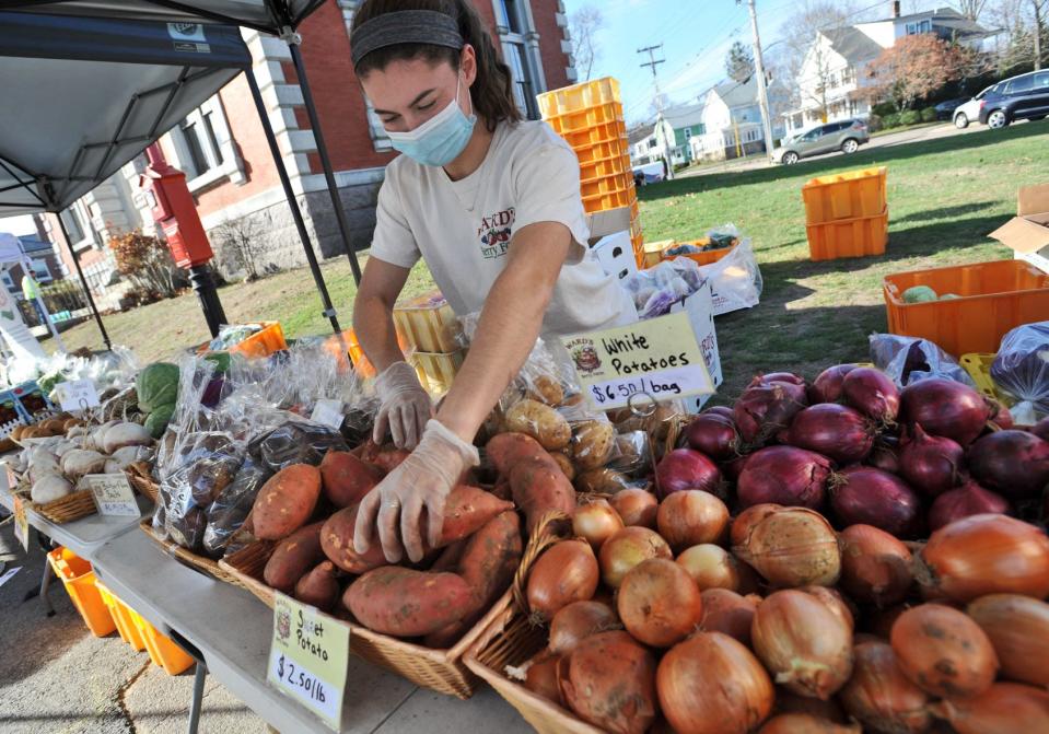 Victoria Pike of Attleboro from Ward's Berry Farm of Sharon stocks fresh vegetables at the Braintree Thanksgiving Holiday Farmers Market at Braintree Town Hall, Saturday, Nov. 21, 2020.