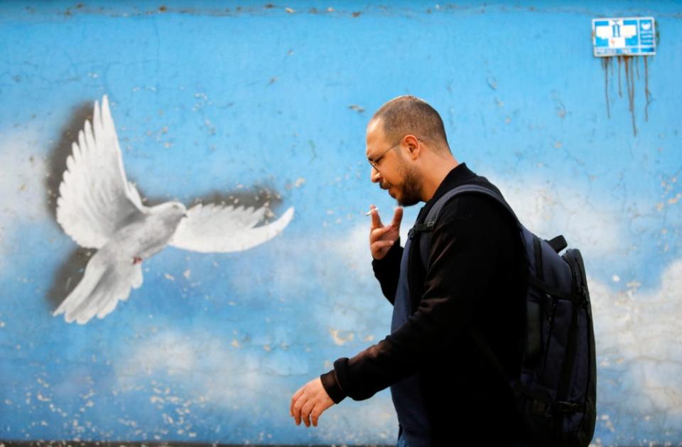 Led by hawks: an Iranian passes a mural of a dove in Tehran (EPA)