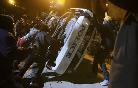 Protesters flip over a Ferguson police car in Ferguson, Missouri, November 25, 2014. REUTERS/Jim Young