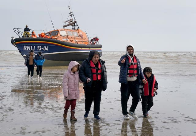 Migrants walk up the beach in Dungeness, Kent