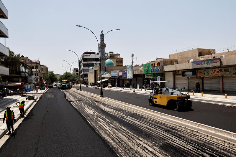 FILE PHOTO: Iraqi workers lay asphalt as a Al-Karada street is paved in Baghdad