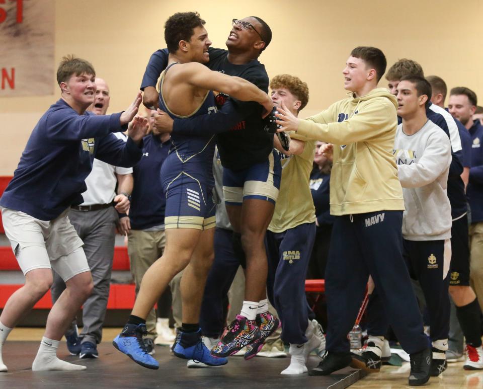 Delaware Military Academy's Hayden Moaney is mobbed by teammates after winning his match at 190 pounds to clinch the DIAA Division I Dual Meet team title against Caravel, Saturday Feb. 18, 2023 at Smyrna High School.