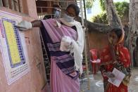 A woman explains the working of an electronic voting machine (EVM) to a voter at a polling station, during the first phase of state elections at Paliganj, in the eastern Indian state of Bihar, Wednesday, Oct. 28, 2020. With an overall declining coronavirus positive trend, Indian authorities decided to hold the first state legislature election since the outbreak of COVID-19. People began voting Wednesday in the country’s third largest state Bihar with of a population of about 122 million people. (AP Photo/Aftab Alam Siddiqui)