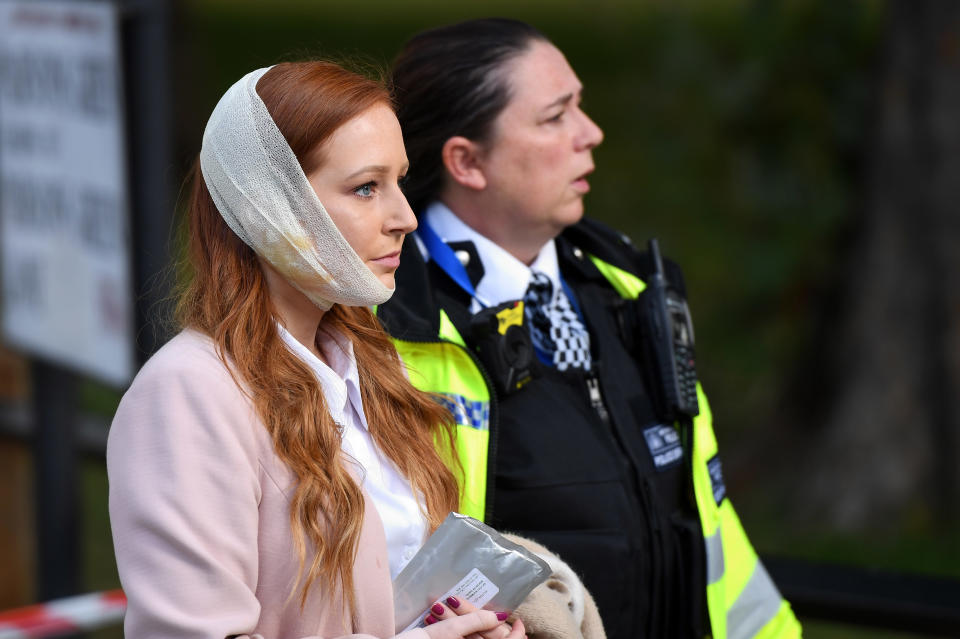 A police officer escorts an injured woman from the scene.