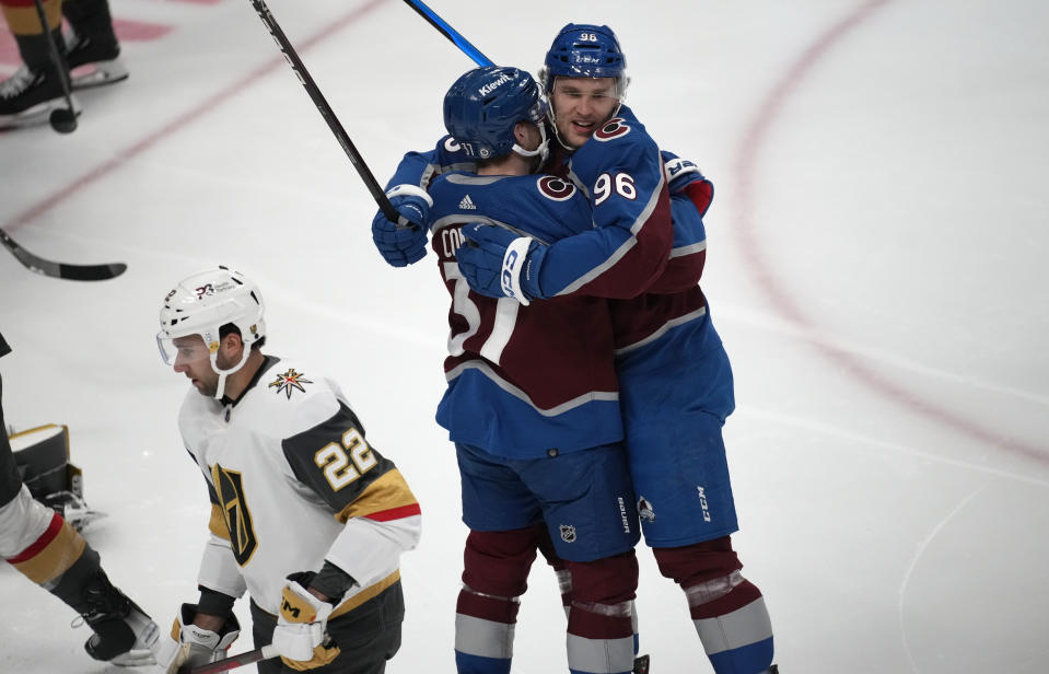 Colorado Avalanche right wing Mikko Rantanen, right, hugs left wing J.T. Compher after scoring as Vegas Golden Knights right wing Michael Amadio skates past in the first period of an NHL hockey game Monday, Feb. 27, 2023, in Denver. (AP Photo/David Zalubowski)