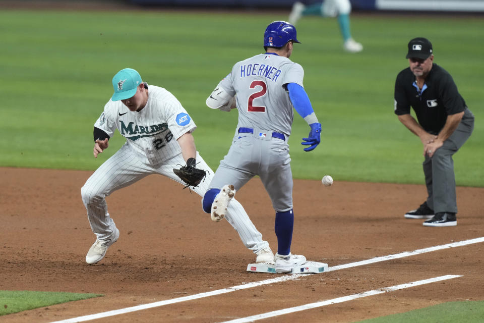 Chicago Cubs' Nico Hoerner (2) is safe on first base as Miami Marlins first baseman Garrett Cooper (26) is not able to catch the ball during the third inning of a baseball game, Friday, April 28, 2023, in Miami. (AP Photo/Marta Lavandier)