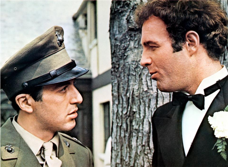 A man in a uniform, talks to a man in a tuxedo in a scene from the film "The Godfather."