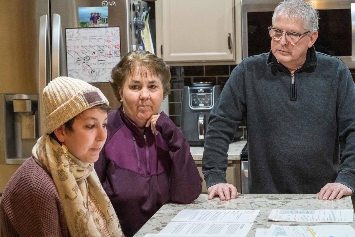 Dan Maccoux, his wife Cathy Maccoux(L) and daughter Olivia Maccoux look at papers on January 16, 2020 in Brooklyn Park, Minnesota - He may be insured and has a six-figure salary but after spending hundreds of thousands of dollars on care for his daughter Olivia, Dan Maccoux expects to be in debt for the rest of his life -- victim of a ferociously expensive US health system that Donald Trump's challengers for the presidency have pledged to overhaul or scrap. (Photo by Kerem Yucel / AFP) (Photo by KEREM YUCEL/AFP via Getty Images)