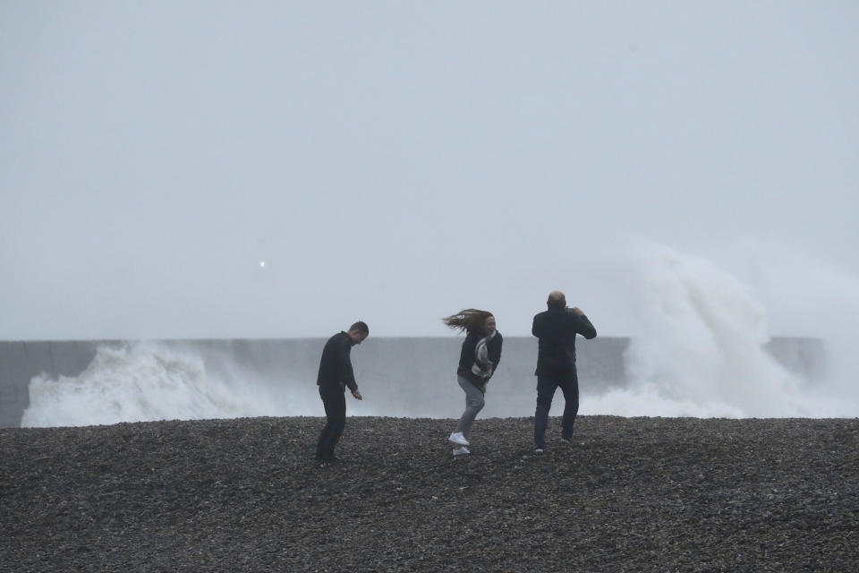 People get blown by the wind as waves crash over the harbour wall as Storm Ciara hits Newhaven, on the south coast of England, Sunday, Feb. 9, 2020. Trains, flights and ferries have been cancelled and weather warnings issued across the United Kingdom and in northern Europe as the storm with winds expected to reach hurricane levels batters the region. (AP Photo/Matt Dunham)