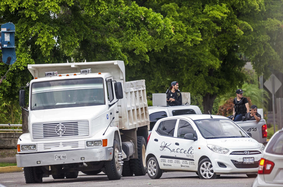 Unidentified gunmen block a street in Culiacan, Mexico, Thursday, Oct. 17, 2019. An intense gunfight with heavy weapons and burning vehicles blocking roads raged in the capital of Mexico’s Sinaloa state Thursday after security forces located one of Joaquín “El Chapo” Guzmán’s sons who is wanted in the U.S. on drug trafficking charges. (AP Photo/Augusto Zurita)