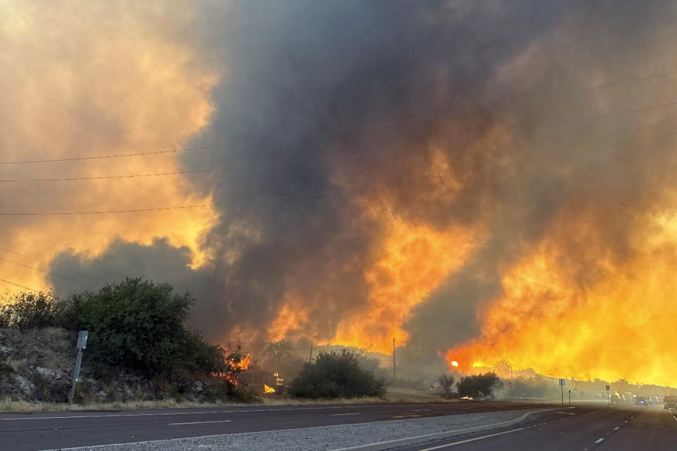 This image provided by the Arizona Department of Forestry and Fire Management shows smoke and flames along a highway near Wickenburg, Ariz., Wednesday, June 12, 2024. Officials say the fire destroyed several homes, prompted evacuations and forced the temporary closure of a highway while crews battled the flames. (Arizona Department of Forestry and Fire Management via AP)