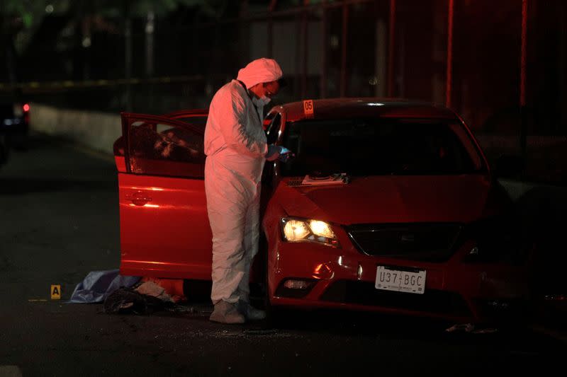 A forensic technician works at a crime scene where unknown assailants attacked a vehicle, in Ecatepec de Morelos