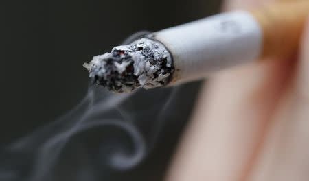 A woman smokes a cigarette in this illustration picture taken in Paris, October 8, 2014. REUTERS/Christian Hartmann/Files