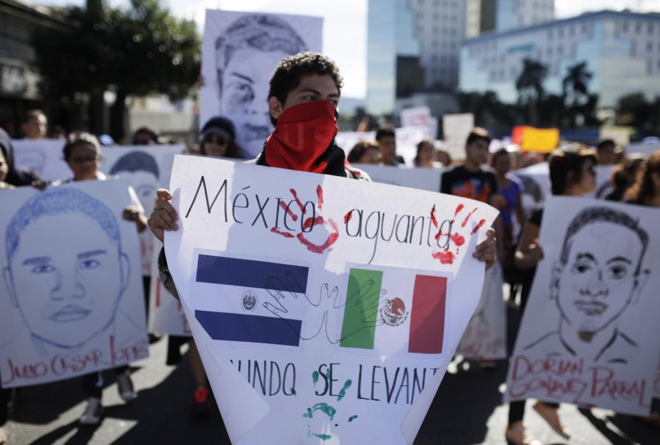 Demonstrators carry sketches of missing Ayotzinapa students during a protest in San Salvador