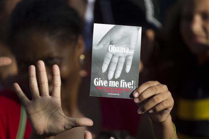 A demonstrator holds a leaflet that refers to the so-called &quot;Cuban Five&quot;, which are celebrated by many in Cuba as national heroes who were spying on armed exile groups in Miami to prevent attacks on their country and victims of Washington&#39;s campaign against the communist-run island, during a march in Havana &quot;For the Five and Against the Terrorism&quot;, September 30, 2014. REUTERS/Alexandre Meneghini (CUBA - Tags: POLITICS CIVIL UNREST)